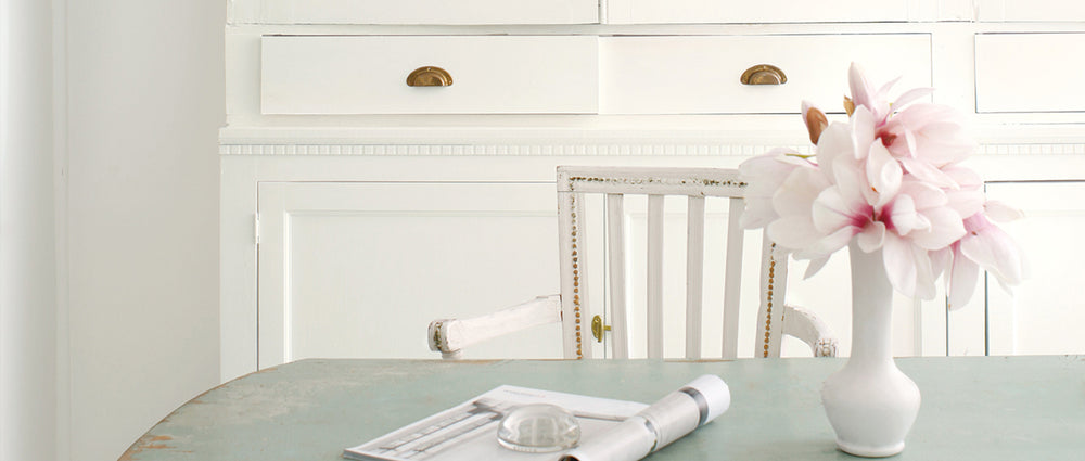 light green table with white flower vase chair and cabinet 